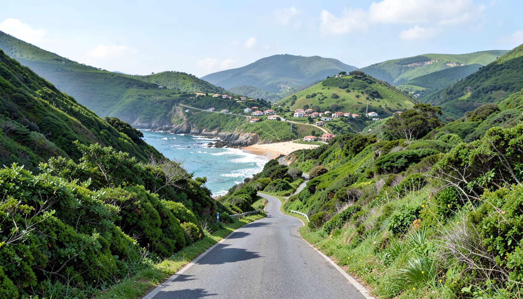 A winding road through lush green hills leading to a small village nestled near a sandy cove on the Atlantic coast